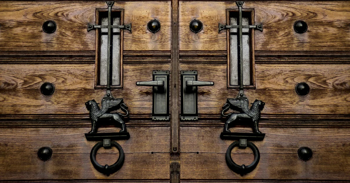 Un corridoio di uffici di sera con porte chiuse e una sola porta socchiusa da cui filtra luce