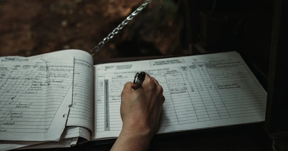 Un quaderno aperto pieno di brevi annotazioni a matita sotto una lampada da scrivania, di sera
