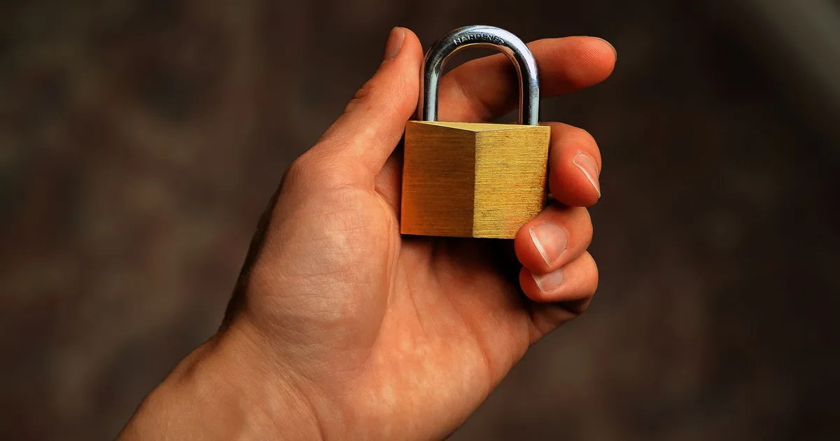 Una chiave nuova appoggiata accanto a un lucchetto chiuso su un tavolo di legno