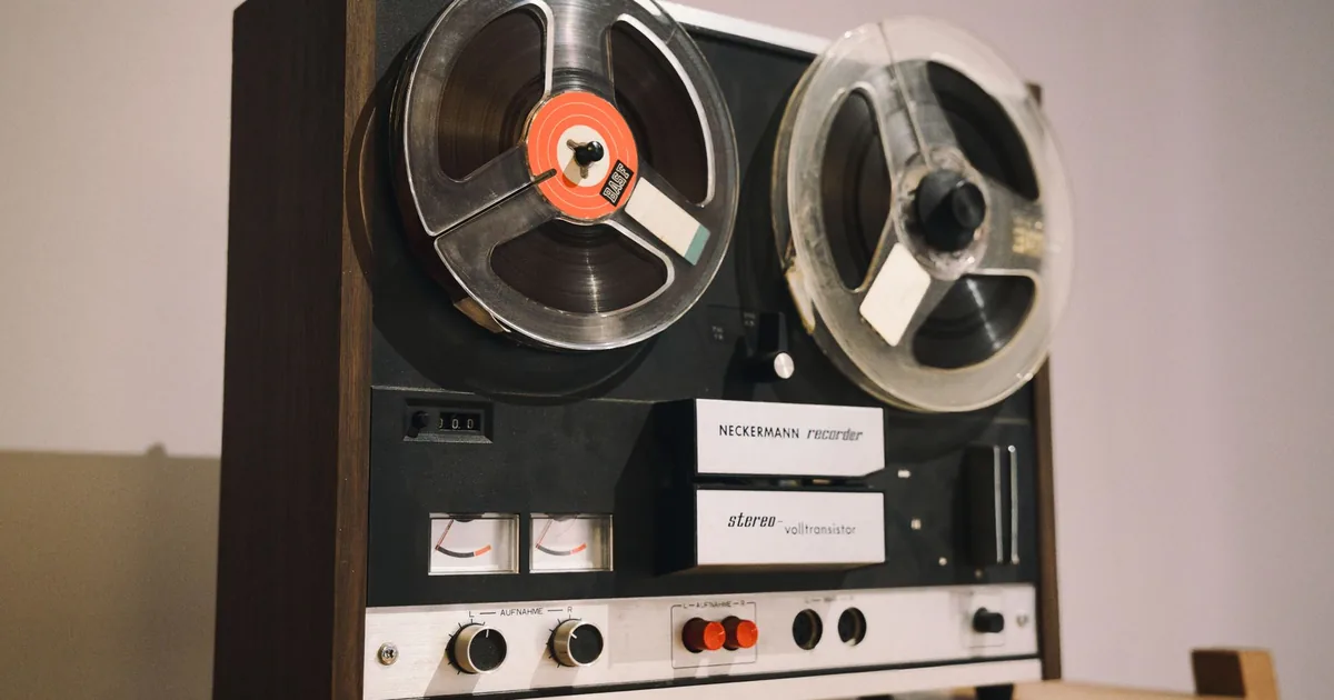 A half-open wooden drawer holding old reels and music tapes