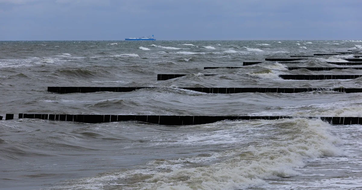 Foto d'archivio, non è il video verificato: una grande nave da carico attraversa onde grigie e agitate sotto un cielo coperto da tempesta, vista da lontano.