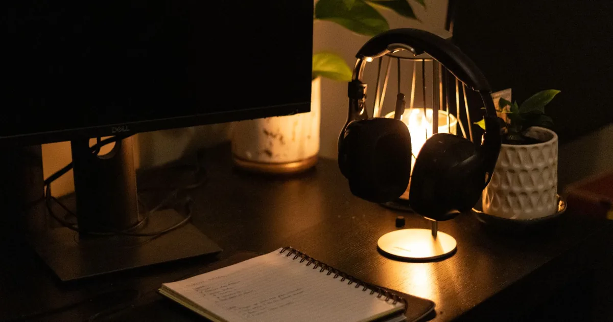 Una mano accende la lampada su una scrivania al buio, sopra un quaderno aperto