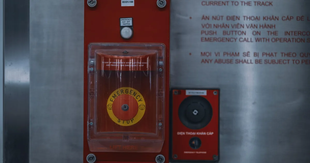A red emergency stop button on an industrial control panel